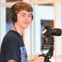 Student smiling holding camera equipment